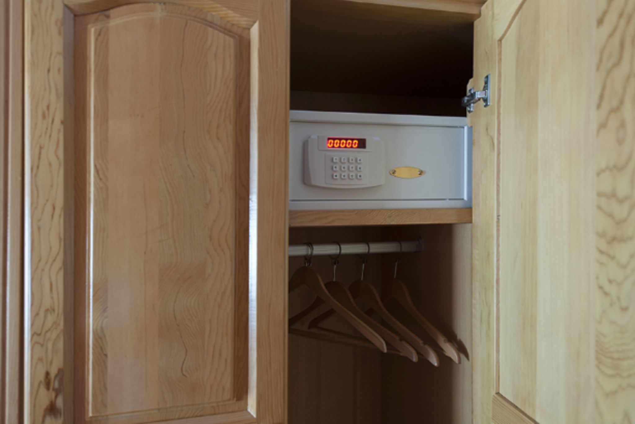 Une armoire en bois dotée d’un verrou numérique et d’une tringle à vêtements à l’intérieur.