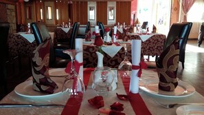 A dining area with tables set for a meal, featuring red rose petals and white napkins. - Dar Eddaya Hôtel (Oulmes)