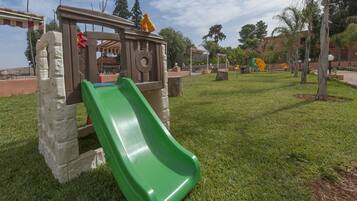 A playground with a green slide and a climbing structure.