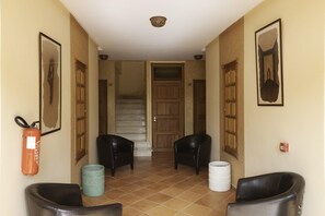 A hallway with two black leather chairs, a fire extinguisher, and a trash bin.
