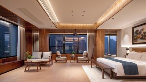 A modern hotel room with a large bed, seating area, and large windows offering a view. - Zhangjiajie Valley Love Holiday Hotel (Zhangjiajie)