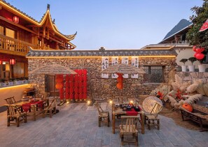 Ein traditioneller chinesischer Innenhof mit Steinmauern, Holzmöbeln und roten Laternen.