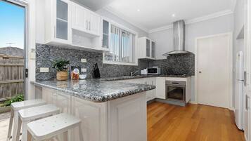 A modern kitchen with granite countertops, white cabinetry, and a built-in oven.