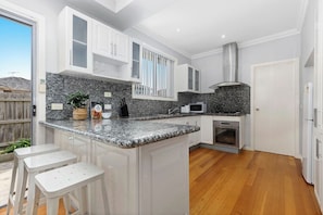 A modern kitchen with granite countertops, white cabinetry, and a built-in oven.