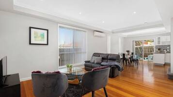 A modern living room with a sofa, chairs, a coffee table, and a TV.