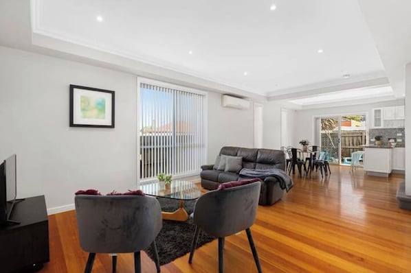 A modern living room with a sofa, chairs, a coffee table, and a TV.