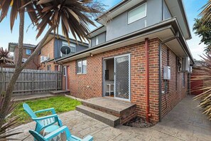 A residential property with a brick exterior, a covered patio area, and a fenced backyard. - Domi Rentals - The Iona Townhouse (Clayton)