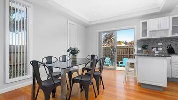 A modern kitchen with white cabinets, a granite countertop, and a dining area with a glass table and chairs.