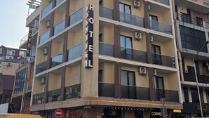 Ein mehrstöckiges Hotel mit Balkonen, ein Geschäft im Erdgeschoss und ein sichtbares Schild für ein Restaurant.