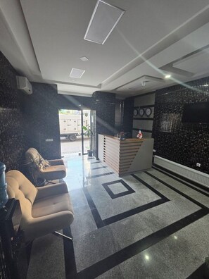 A reception area with a reception desk, seating, and a clock on the wall. - Hotel Corner (Batumi)