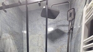 Eine Duschkabine mit Glastür, Handbrause und Wandarmatur.