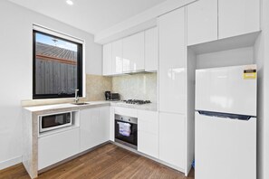 A modern kitchen with white cabinetry, a built-in oven, a microwave, a gas stove, and a refrigerator.