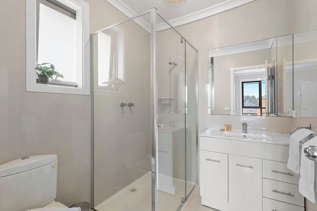 Une salle de bain moderne avec une douche à parois de verre, un lavabo blanc et un grand miroir.