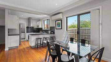 A modern kitchen with white cabinets, a black countertop, and a dining area with a glass table and black chairs.