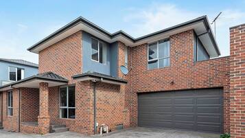 A two-story residential building with a brick facade, a garage, and a covered porch area.