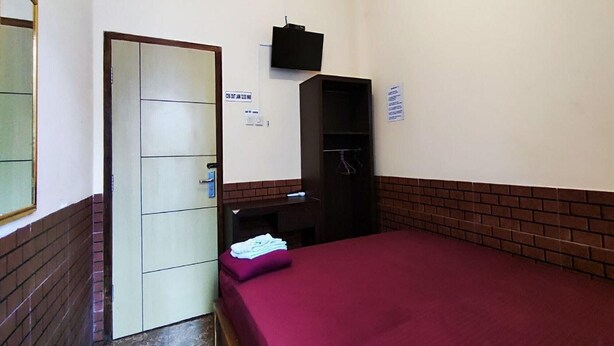 Ein Zimmer mit einem Bett, einem Kleiderschrank, einem Spiegel und einer Tür.
