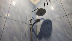 Eine Dusche mit Handbrause und einer an der Wand montierten Bedienung.