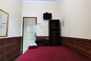 A room with a bed, a desk, a television, and a door. - Oyo 93749 Aksana Homestay Syariah (Purwokerto)