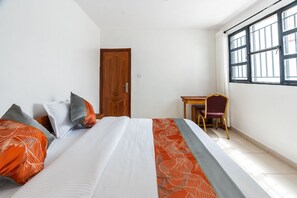 A hotel room with a bed, a desk, and a chair.