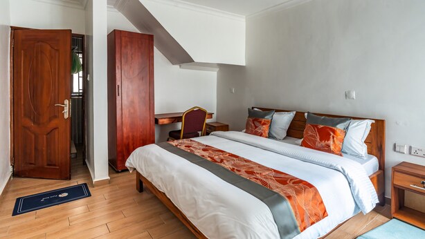A hotel room with a large bed, a desk, and a wardrobe. - Nzeli Inn Hotel (Kigali)