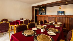 A restaurant with tables set for dining, featuring a wooden panel wall and a hanging light fixture. - Nzeli Inn Hotel (Kigali)