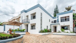 A modern two-story building with a flat roof, large windows, and a paved courtyard. - Nzeli Inn Hotel (Kigali)