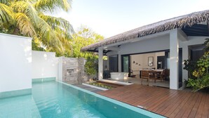 A modern poolside area with a wooden deck, a hot tub, and a dining area with a table and chairs. - Noku Maldives (Noonu Atoll)