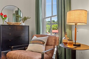 A room with a brown leather armchair, a black dresser, a round table with a lamp, and a bottle of liquor. - 2mi to Buffalo Trace > GameRoom > HotTub > FirePit (Frankfort)