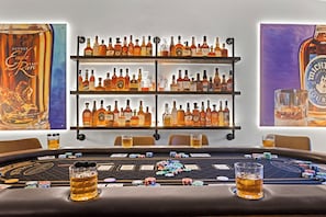 Ein Kasinospieltisch mit Pokerchips und Karten, umgeben von Regalen voller verschiedener Spirituosenflaschen.