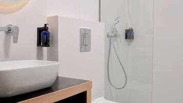 A modern bathroom with a white sink, toilet, and shower.