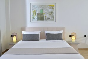 Een hotelkamer met een bed, twee bedlampen, een lijst met abstract schilderij en een nachtkastje.