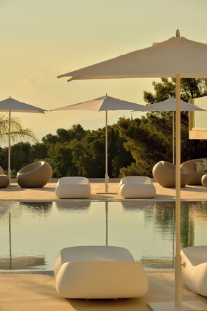A poolside area with modern lounge chairs and umbrellas, surrounded by trees and a clear sky. - Althea Resort & Spa (Xylokastro-Evrostina)