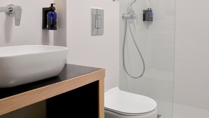 Une salle de bain moderne avec un lavabo, des toilettes et une douche, le tout de couleur blanche.