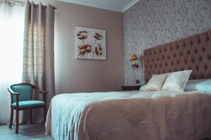 A bedroom with a tufted headboard, a single bed with pillows, a chair, a wall-mounted lamp, and a floral artwork. - La Morona Hotel (Moron de la Frontera)
