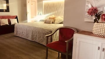 A bedroom with a bed, a red chair, a white cabinet, and a door leading to another room.