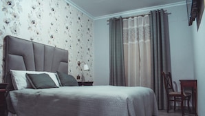 A bedroom with a bed, nightstands, a chair, and a window with curtains. - La Morona Hotel (Moron de la Frontera)