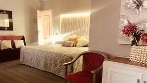 A bedroom with a bed, a red chair, a white cabinet, and a door leading to another room. - La Morona Hotel (Moron de la Frontera)