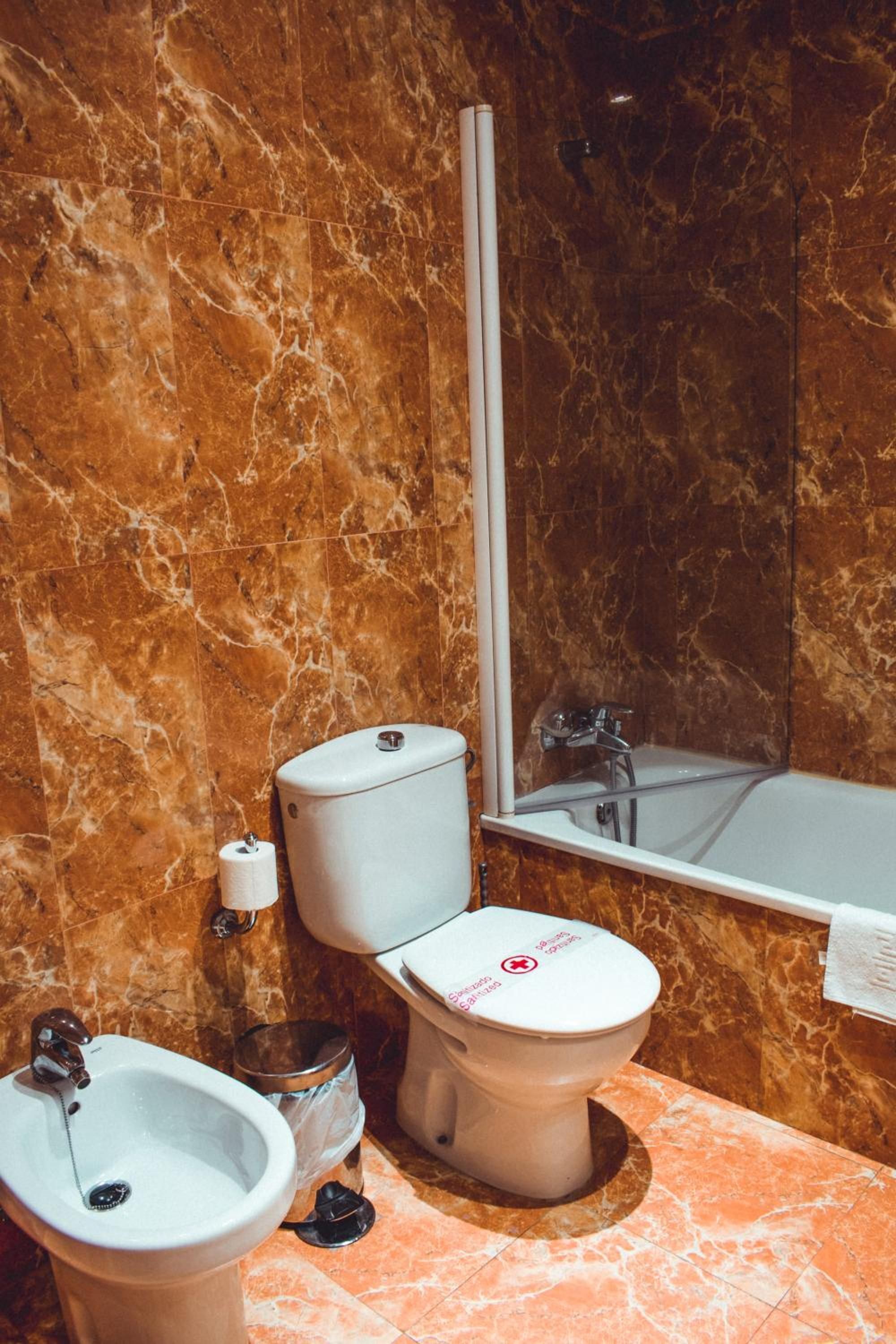 A bathroom with a toilet, bidet, and sink, all with marble walls.