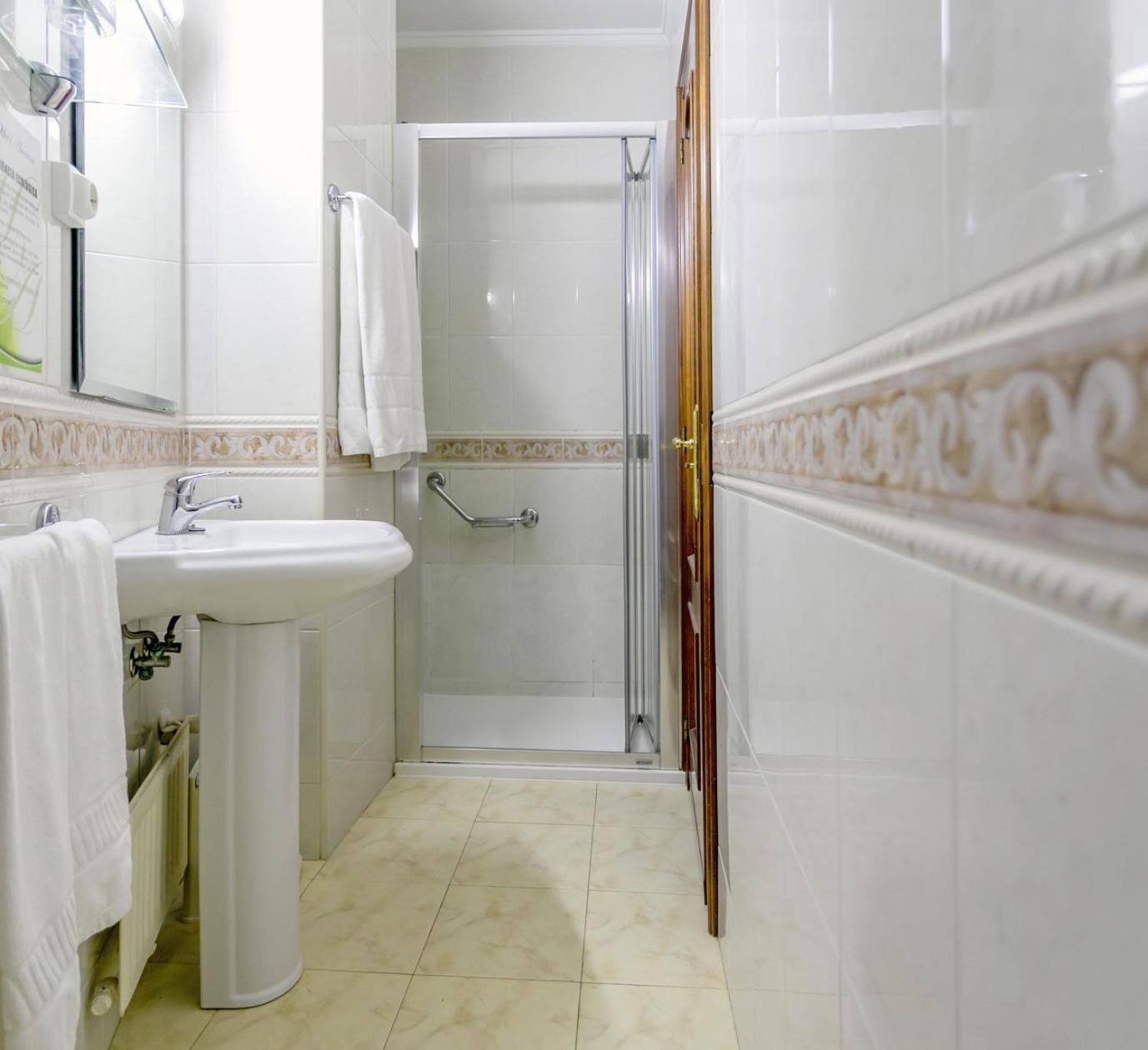 Un baño con lavamanos, espejo y ducha.