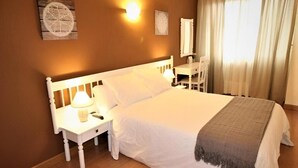 A hotel room with a large bed, a bedside table with a lamp, a desk with a chair, and a window with curtains. - Hotel Amv Rica Ferrol (Ferrol)