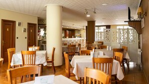 A restaurant with wooden tables and chairs, a tiled floor, and a decorative partition with intricate cutouts. - Hotel Amv Rica Ferrol (Ferrol)