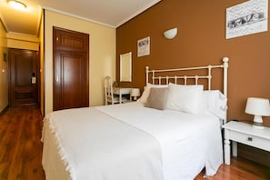 Un dormitorio con una cama blanca, una puerta de madera, un escritorio con una silla y una pared con un letrero que dice 'LOVE'.