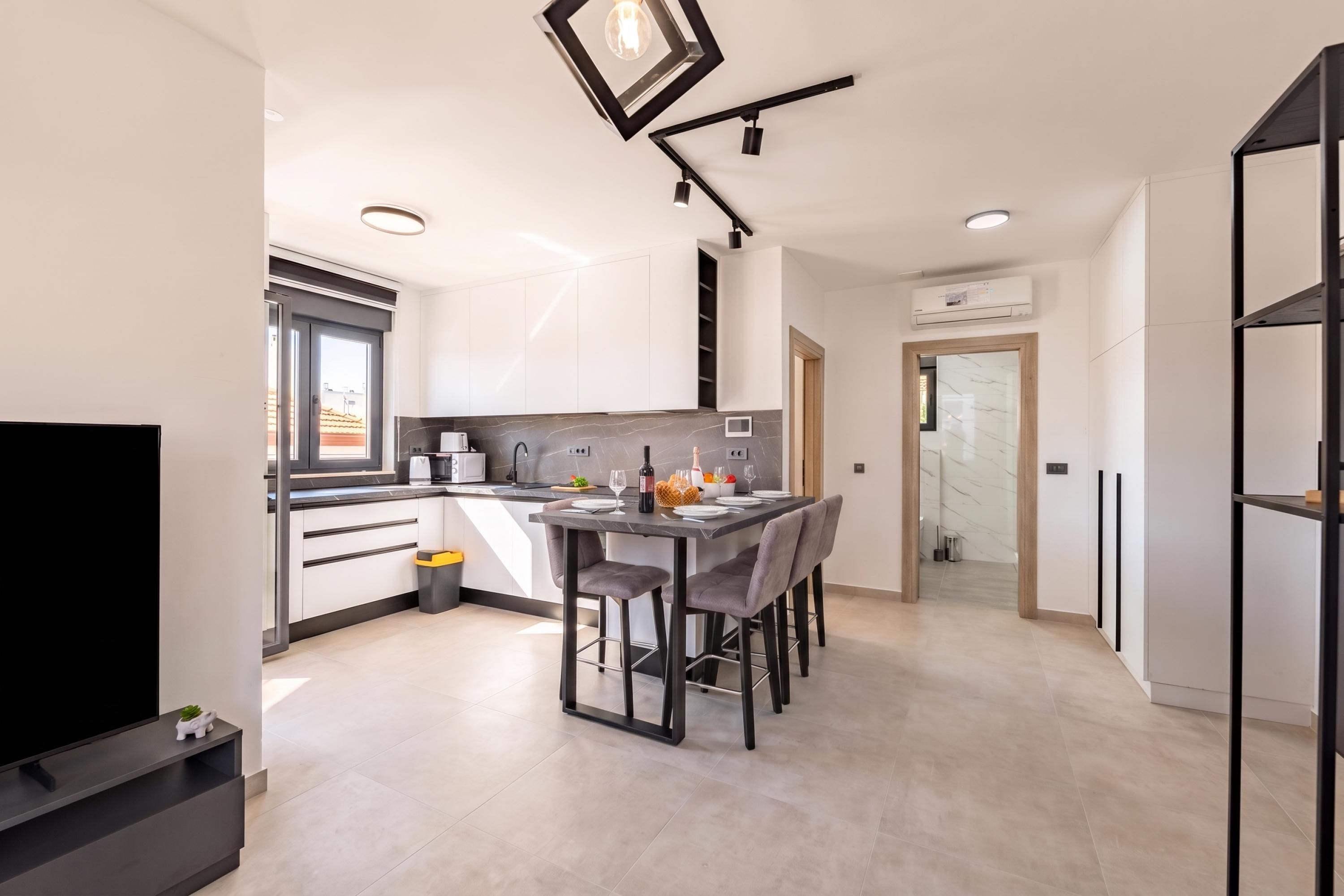 Een moderne keuken met een eethoek, inbouwapparatuur en een flatscreen televisie.