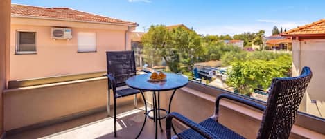 Un balcón con dos sillas y una mesa, con vista a una zona residencial con casas y árboles.