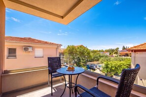 Ein Balkon mit zwei Stühlen und einem Tisch, mit Blick auf ein Wohngebiet mit Häusern und Bäumen.