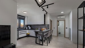 Uma cozinha moderna com área de jantar, armários brancos e mesa com moldura preta.