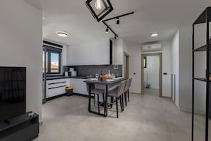 Eine moderne Küche mit Essbereich, weißen Schränken und einem Tisch mit schwarzem Rahmen.
