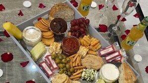A glass table with a variety of snacks and drinks, surrounded by rose petals. - Inviting 1 Bed House In Bradford (Bradford)