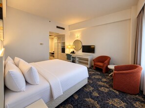 Una habitación de hotel con cama, escritorio, silla, televisión y armario.