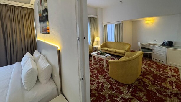 A hotel room with a bed, a sofa, a desk, and a chair. - Royal Park Hotel (Kajang)